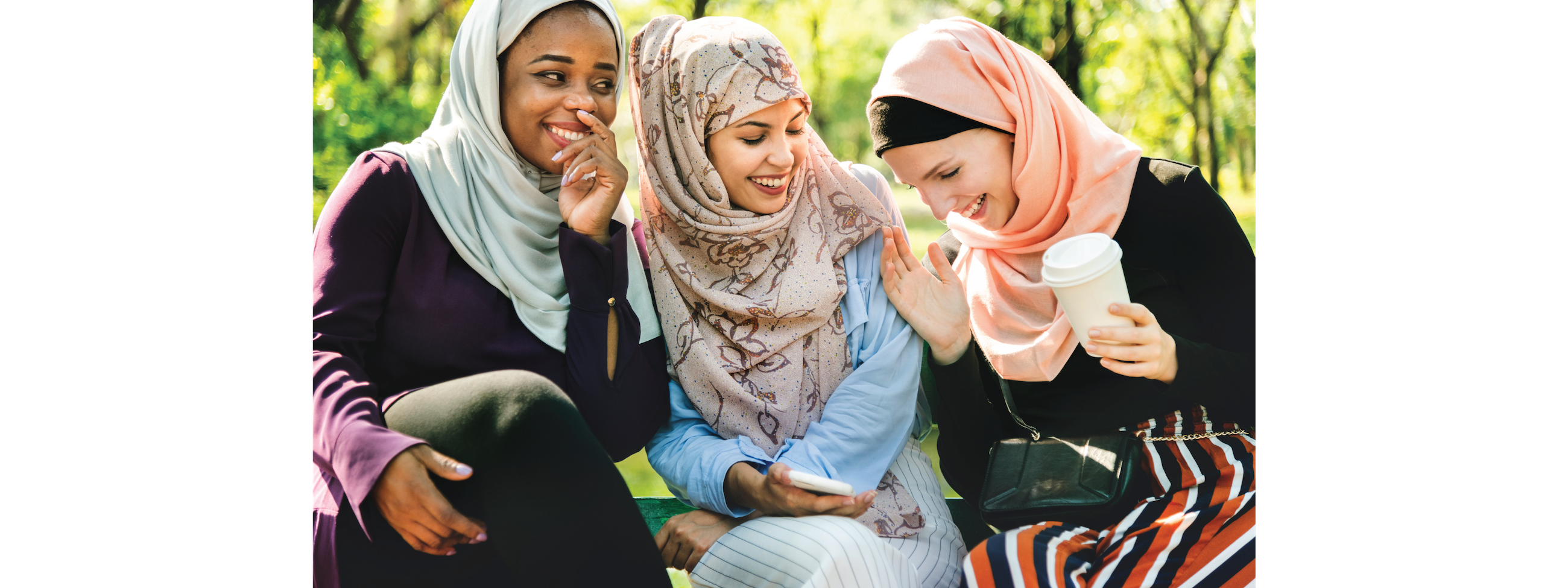 Three women wearing hijabs and laughing.